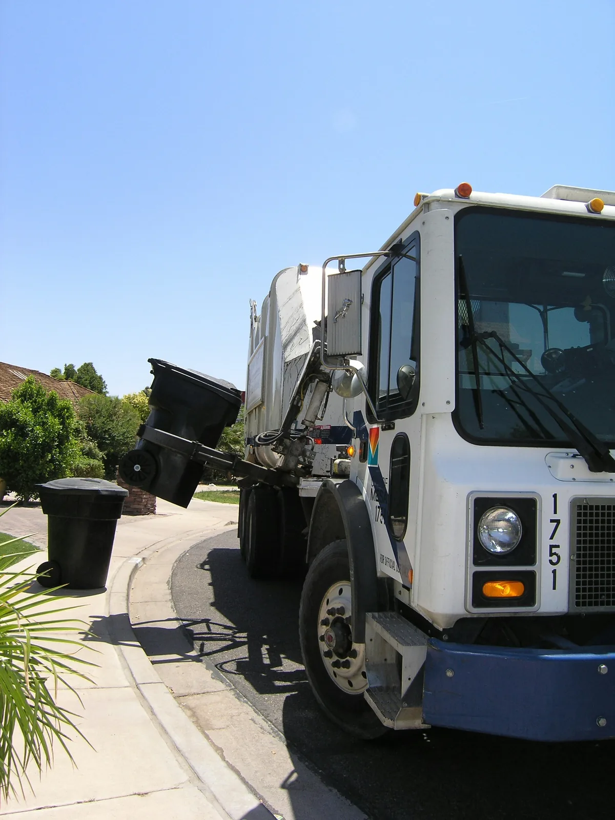 An automated side-load truck lifting a kerbside cart