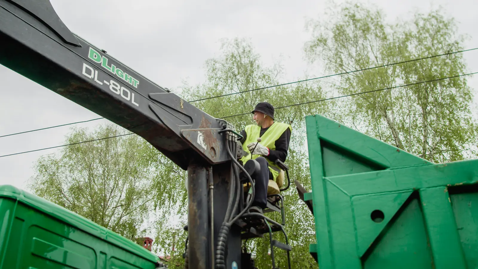 A grapple crane loading green containers