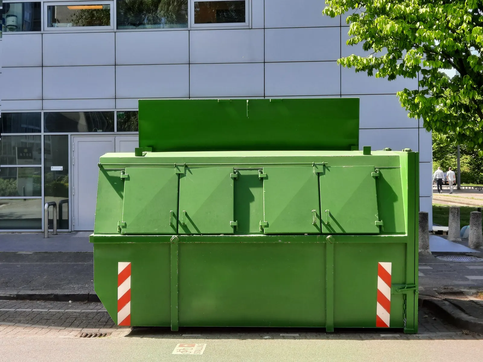 A green container with the lid open outside an office